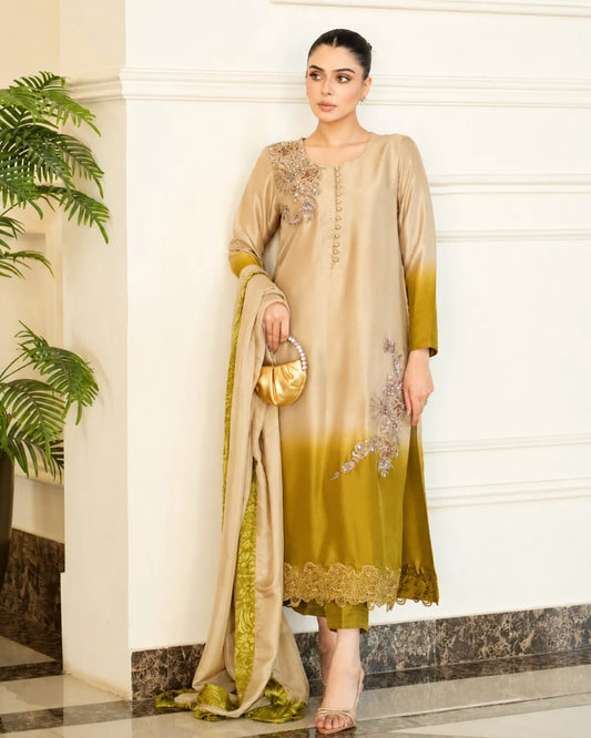Woman wearing a beige and green dress with embroidery, holding a gold handbag indoors.