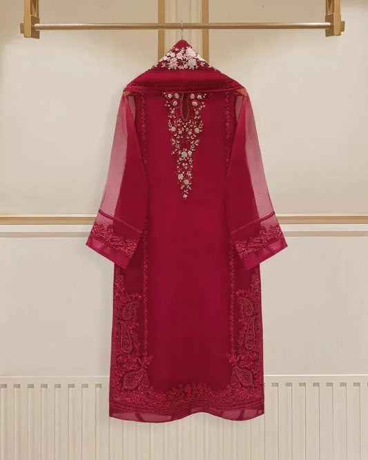 Red embroidered dress on a hanger against a white wall.