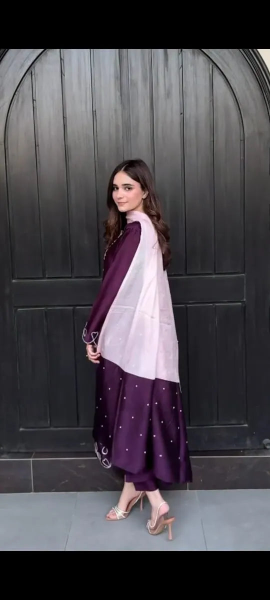 Woman wearing a purple and white traditional outfit against a dark background