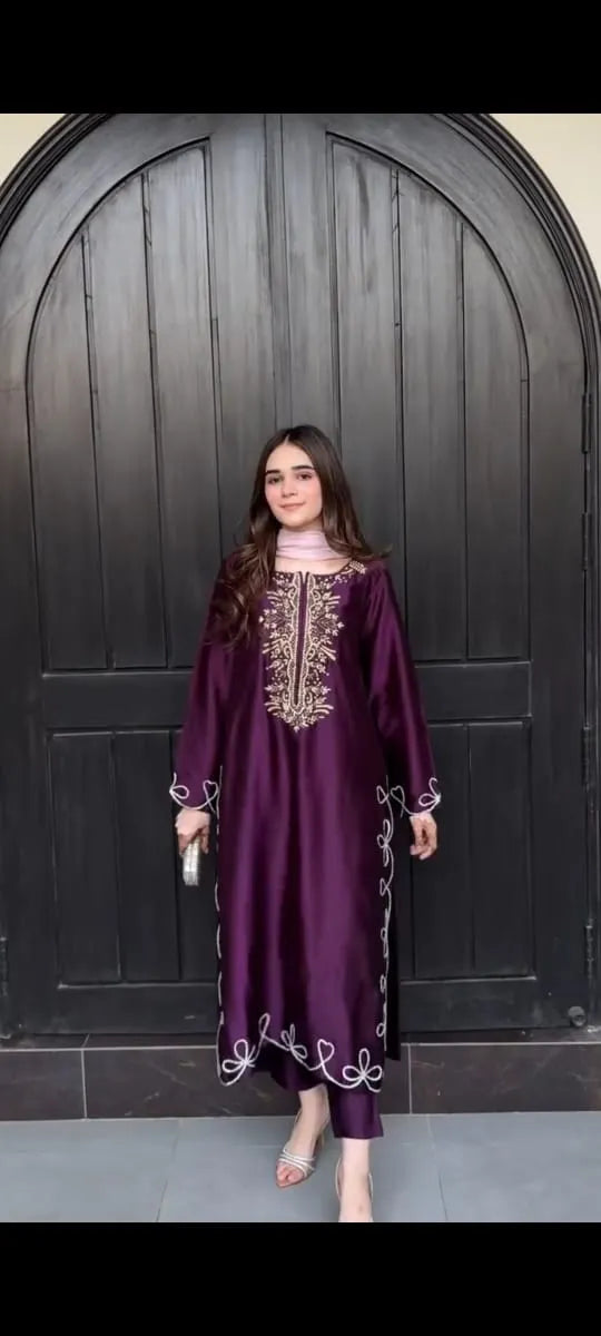Woman wearing a purple dress with gold embroidery in front of a dark wooden door.