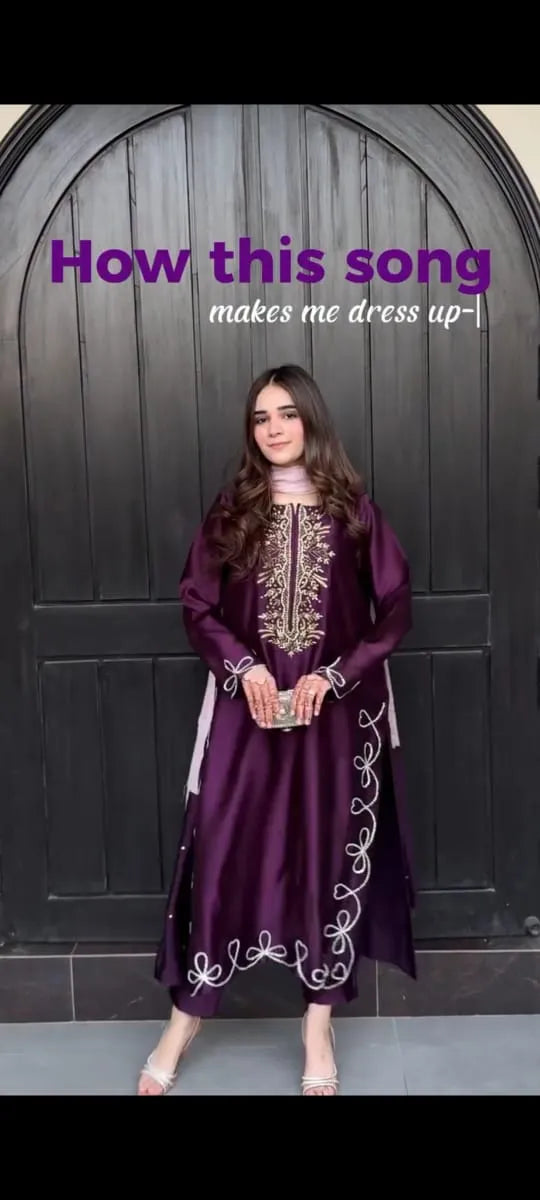 Woman in a purple embroidered dress standing in front of a dark wooden door with text overlay.