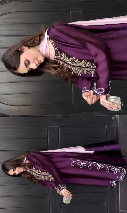 Woman wearing a purple embroidered dress against a dark background