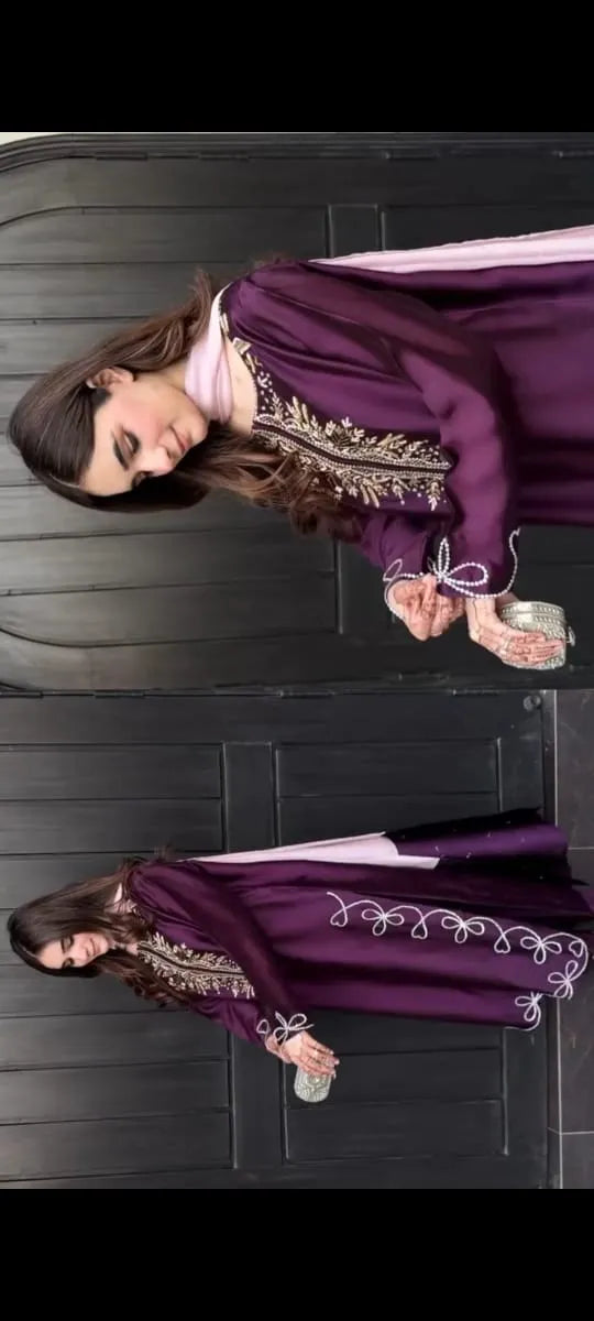 Woman wearing a purple traditional outfit with intricate designs on a dark floor.