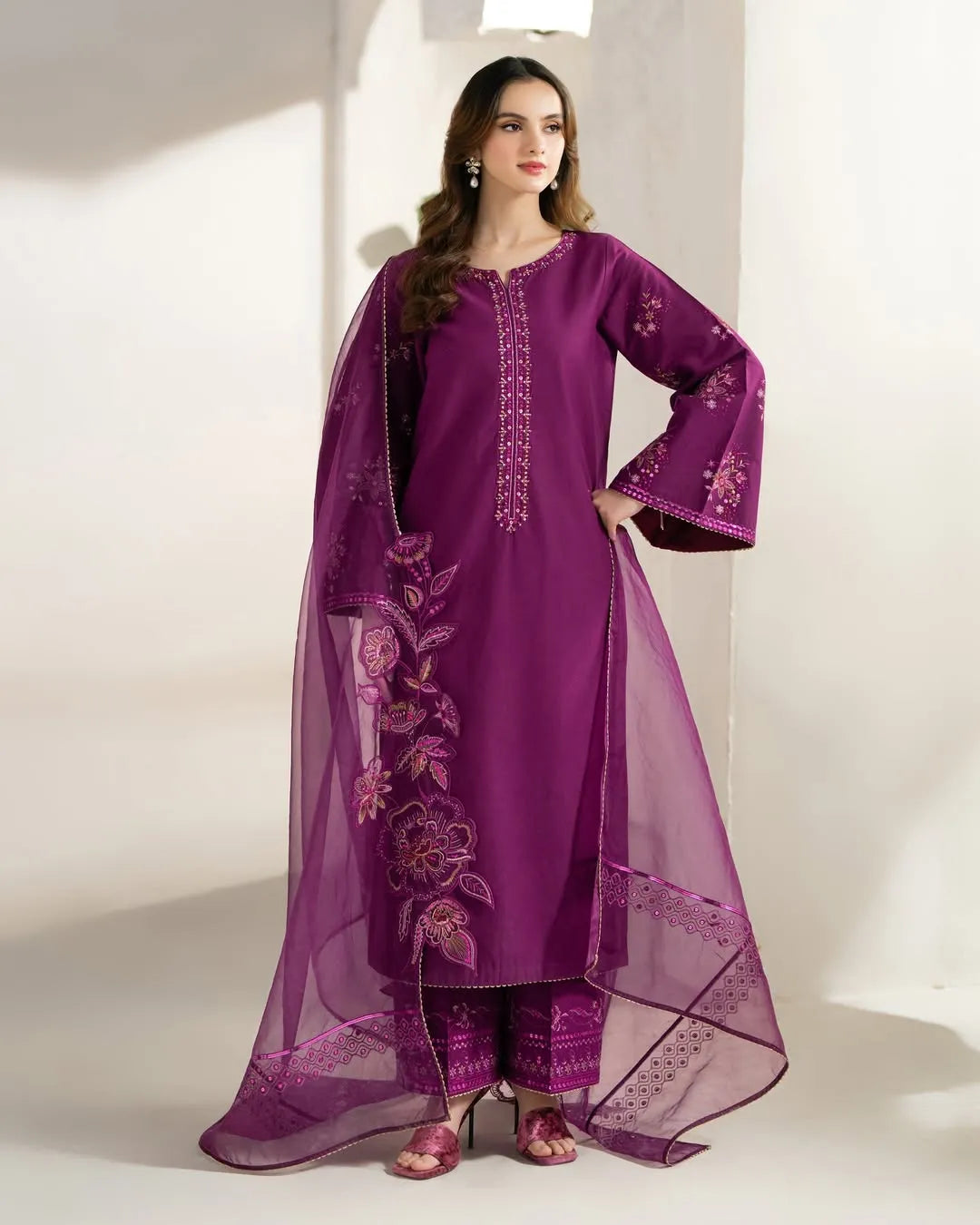 Woman wearing a purple embroidered outfit with a sheer dupatta on a white background