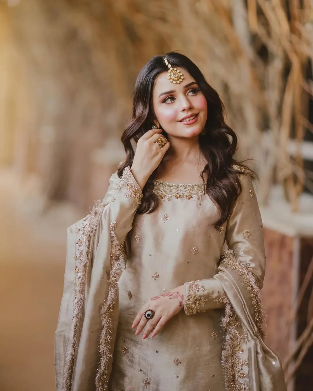 Woman in a beige embroidered traditional outfit with a blurred natural background