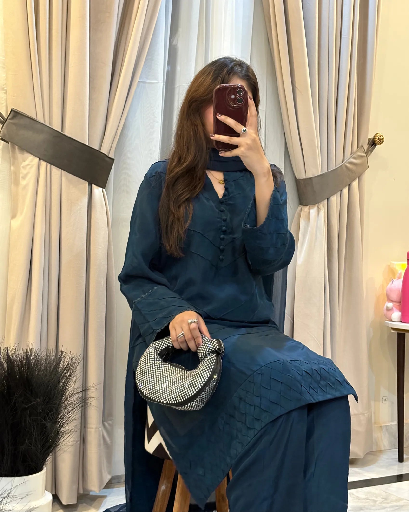 Woman taking a mirror selfie wearing a blue outfit with a textured pattern, holding a small handbag.