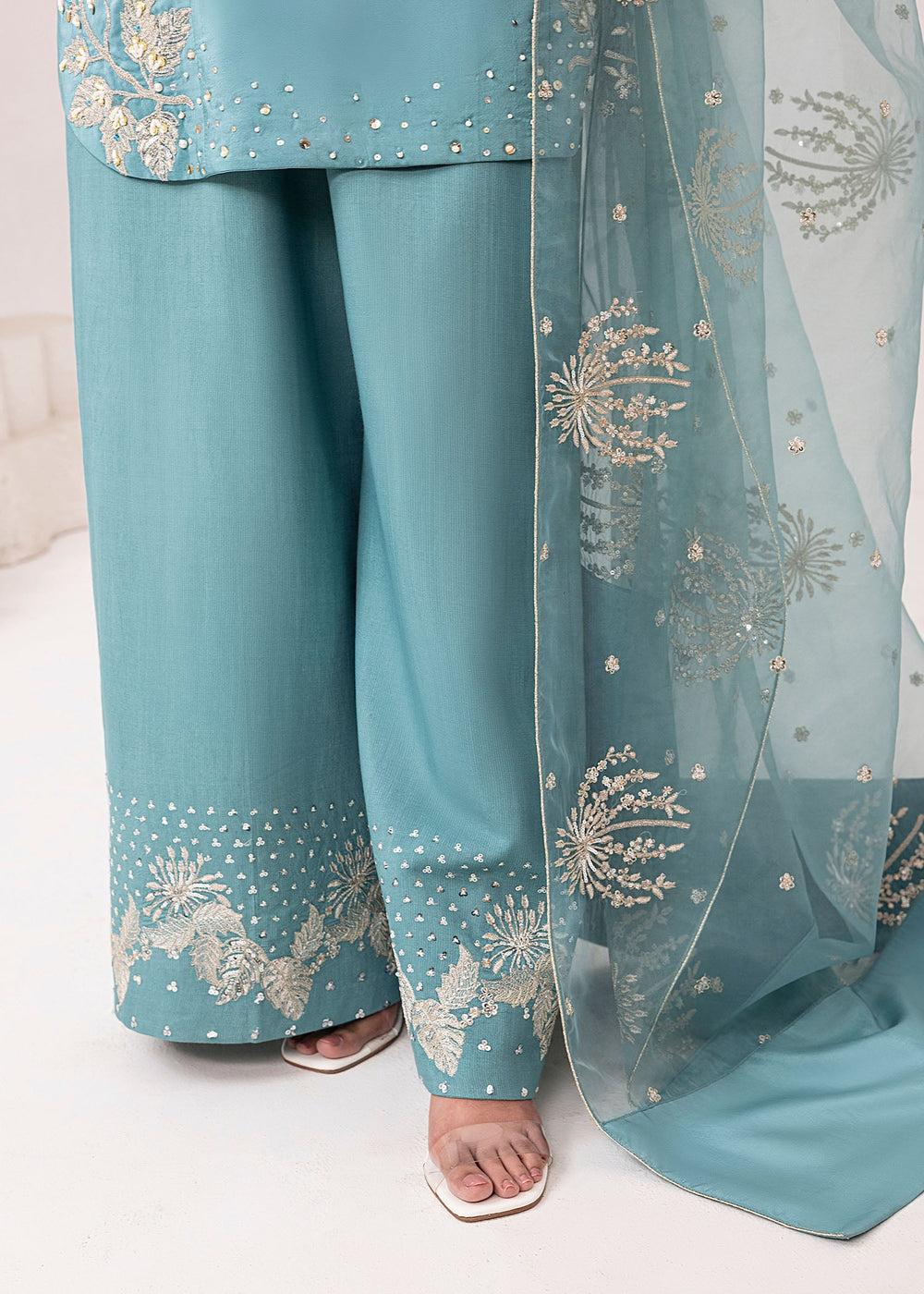 Teal traditional outfit with floral embroidery on a white background