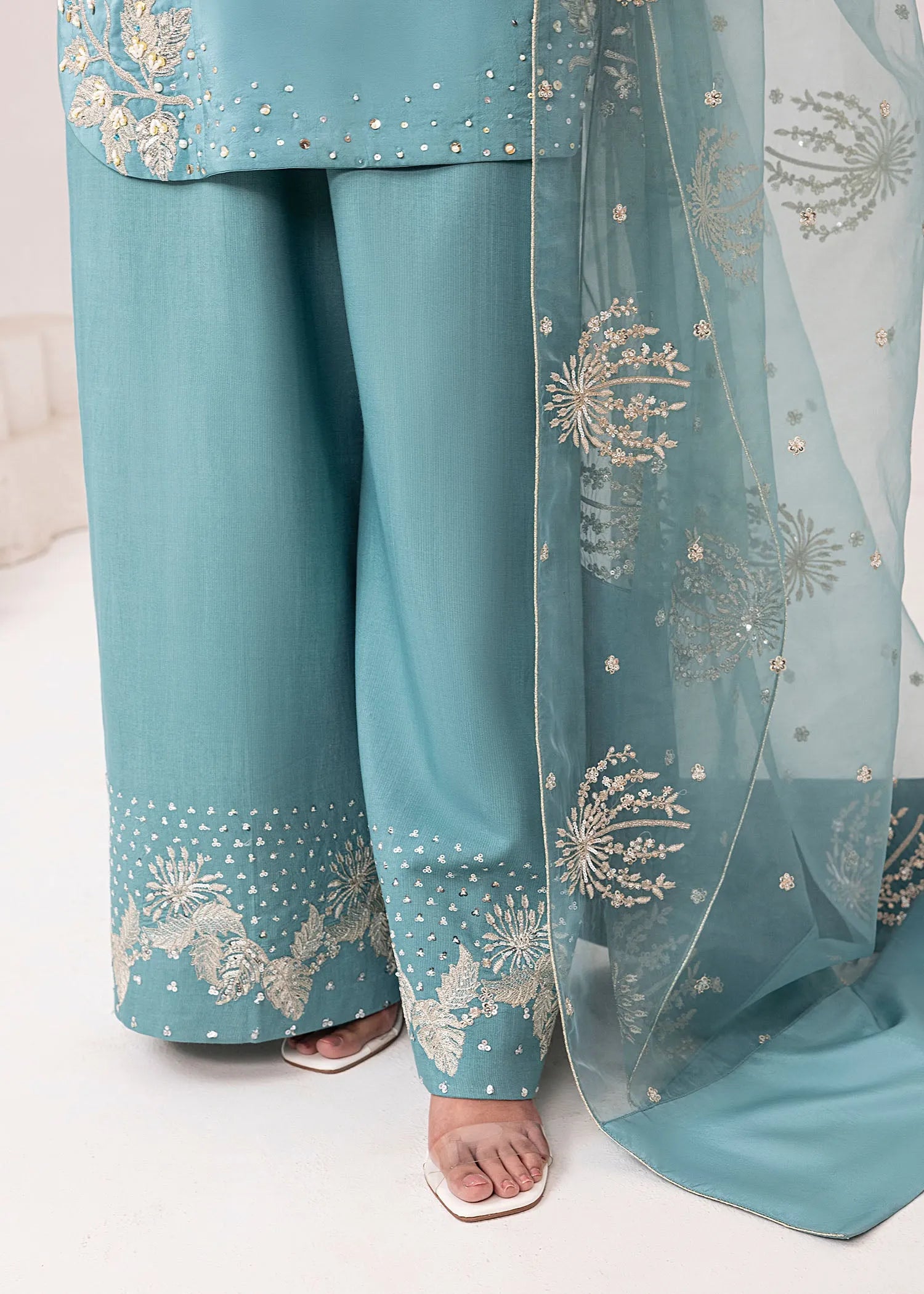 Teal traditional outfit with floral embroidery on pants and dupatta against a neutral background