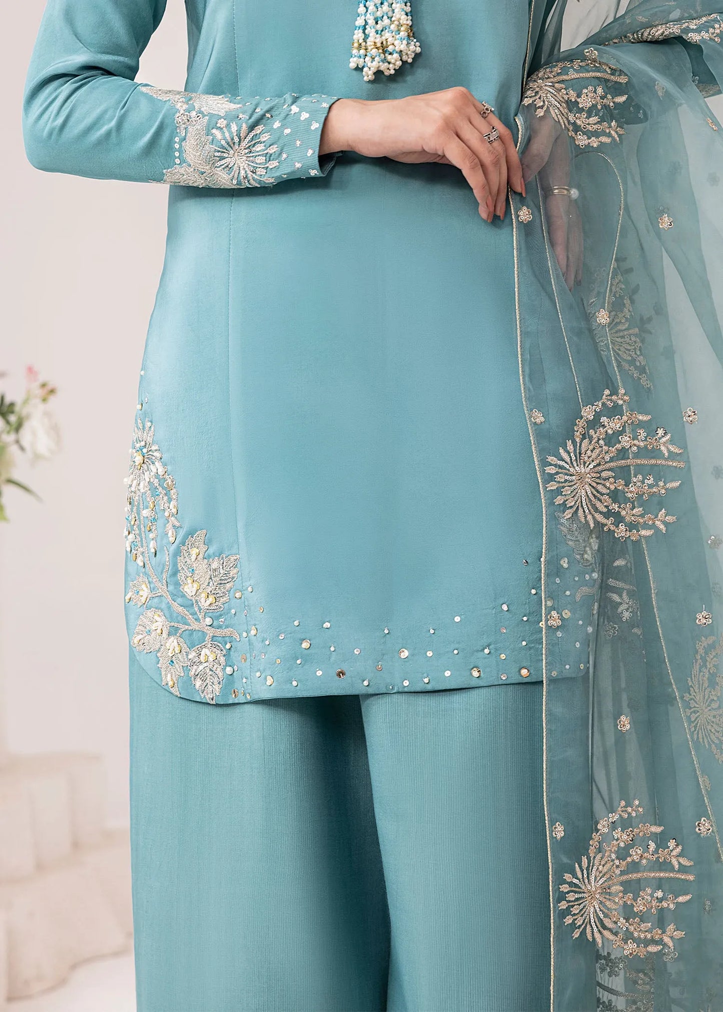 Teal traditional outfit with intricate gold embroidery on a neutral background