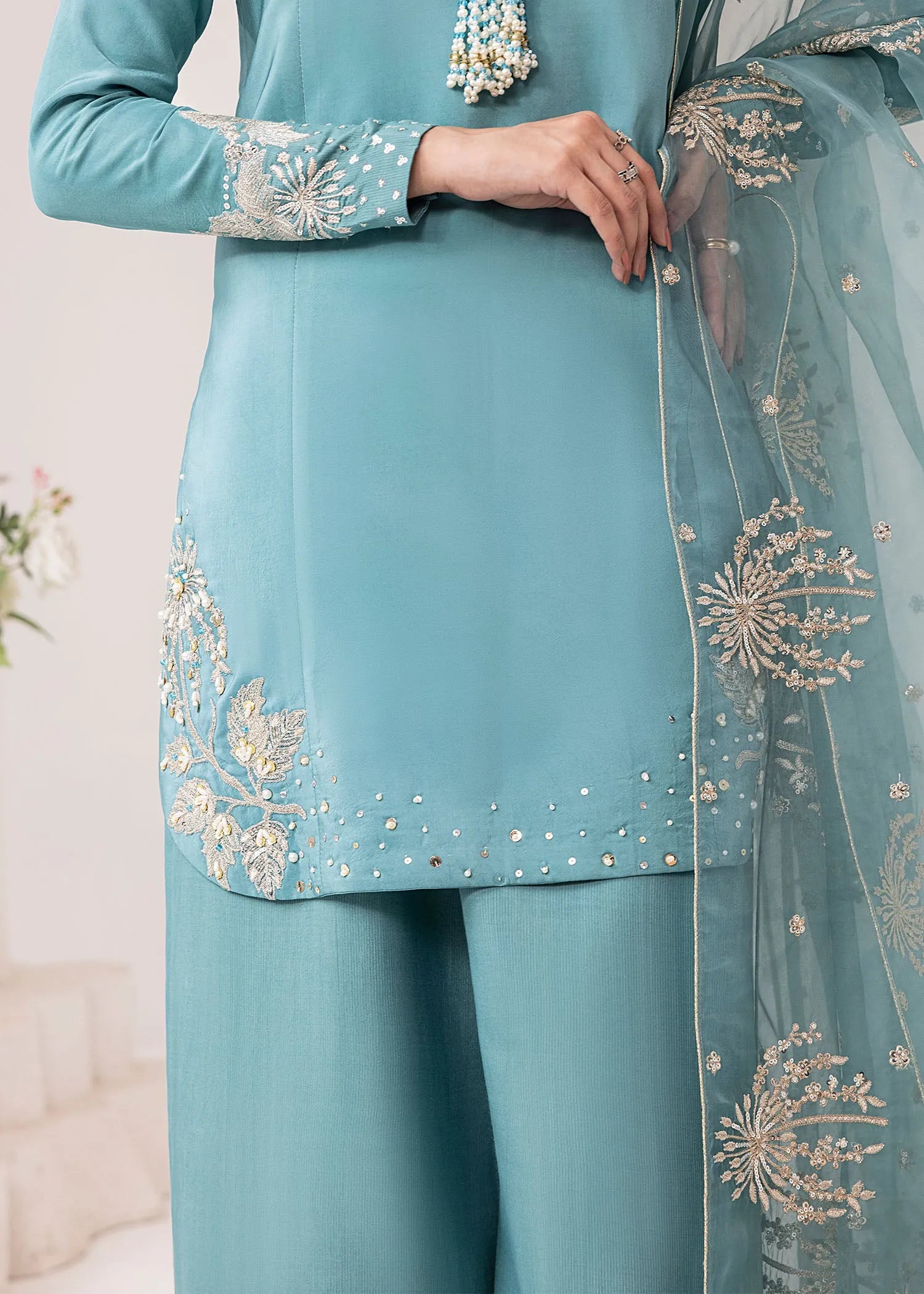 Teal traditional outfit with intricate gold embroidery on a neutral background