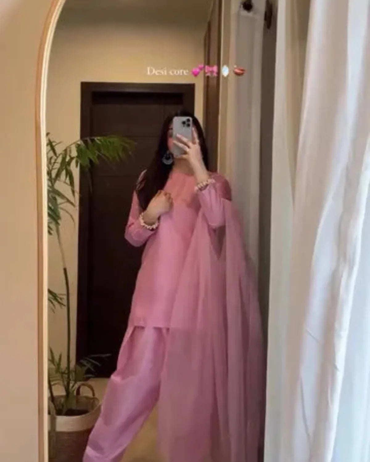 Person wearing a pink outfit taking a mirror selfie.