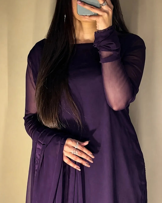 Woman wearing a purple dress with sheer sleeves against a beige background