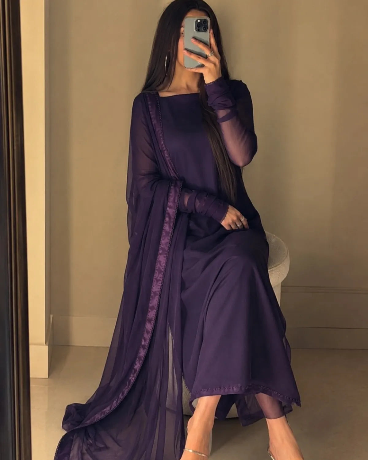 Person wearing a long purple dress sitting on a chair.