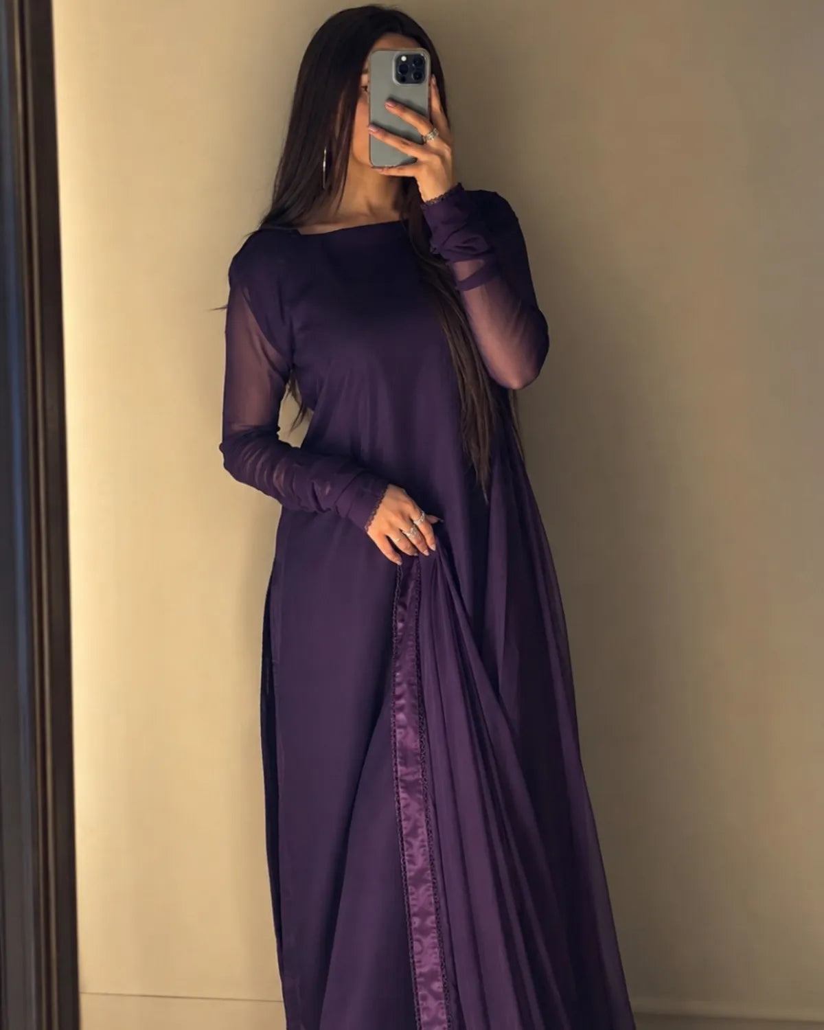 Person wearing a long purple dress taking a mirror selfie.