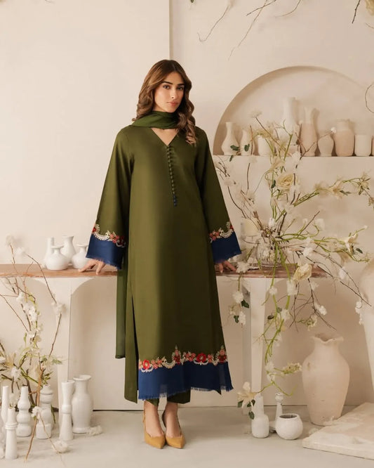 Woman wearing a green dress with blue accents in a decorative room.