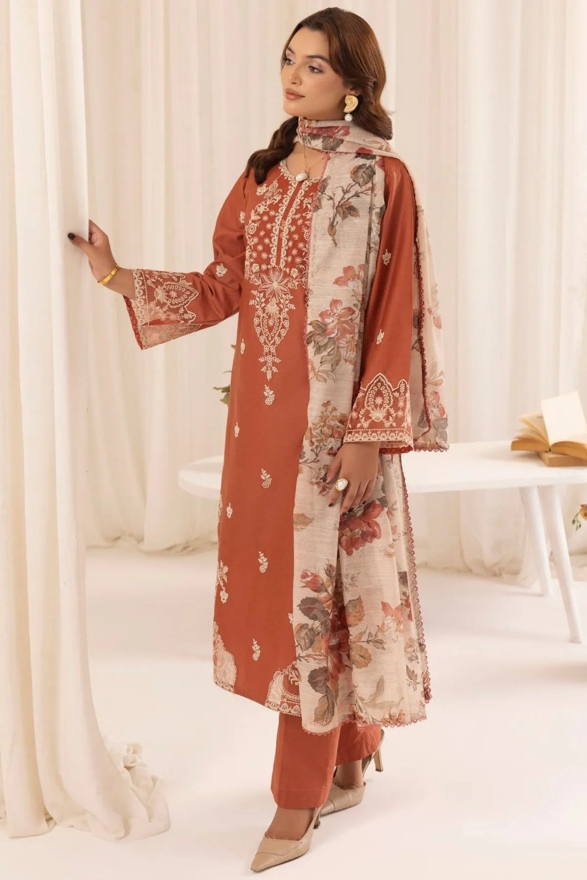 Woman wearing a traditional outfit with floral patterns in a white room.
