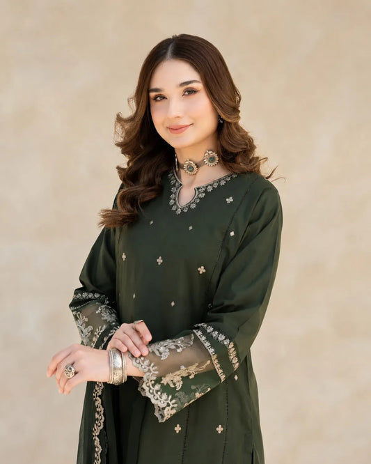 Woman wearing a dark green traditional outfit with intricate designs on a beige background