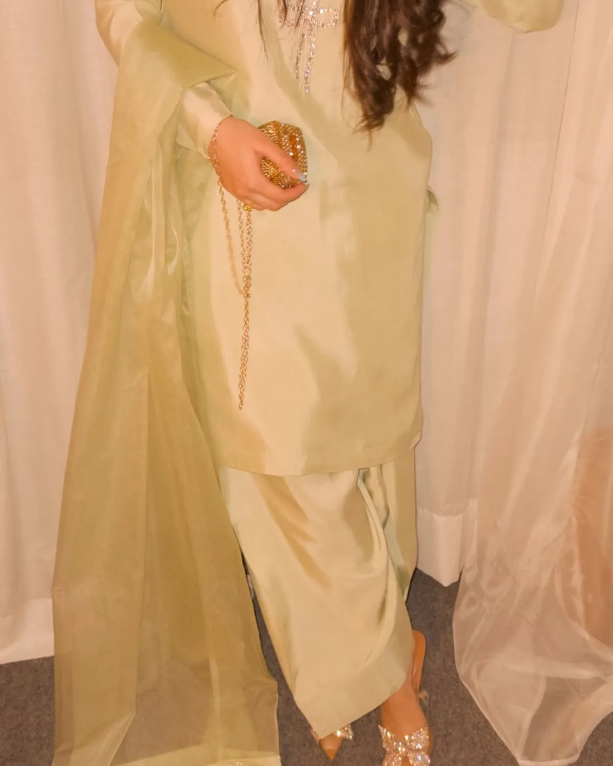 Person wearing a light green traditional outfit with a white background
