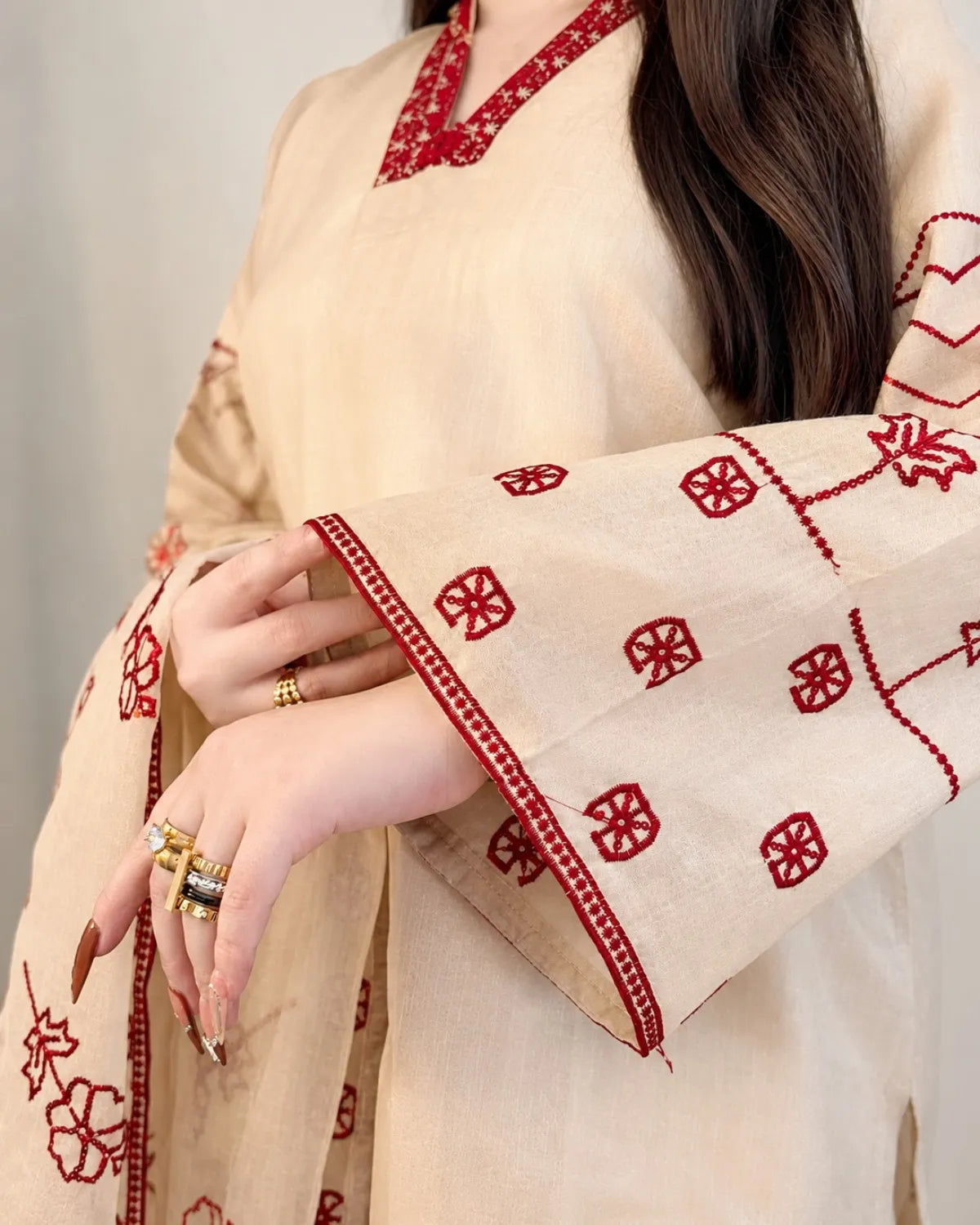 Beige dupatta with red patterns draped over a person against a neutral background