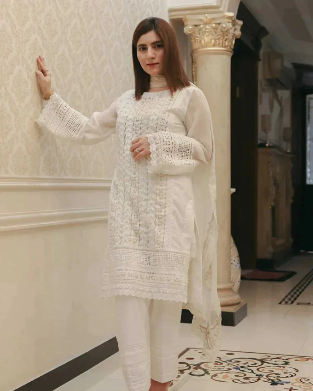 Woman in a white traditional outfit standing indoors.