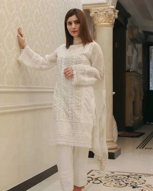 Woman in a white traditional outfit standing indoors.