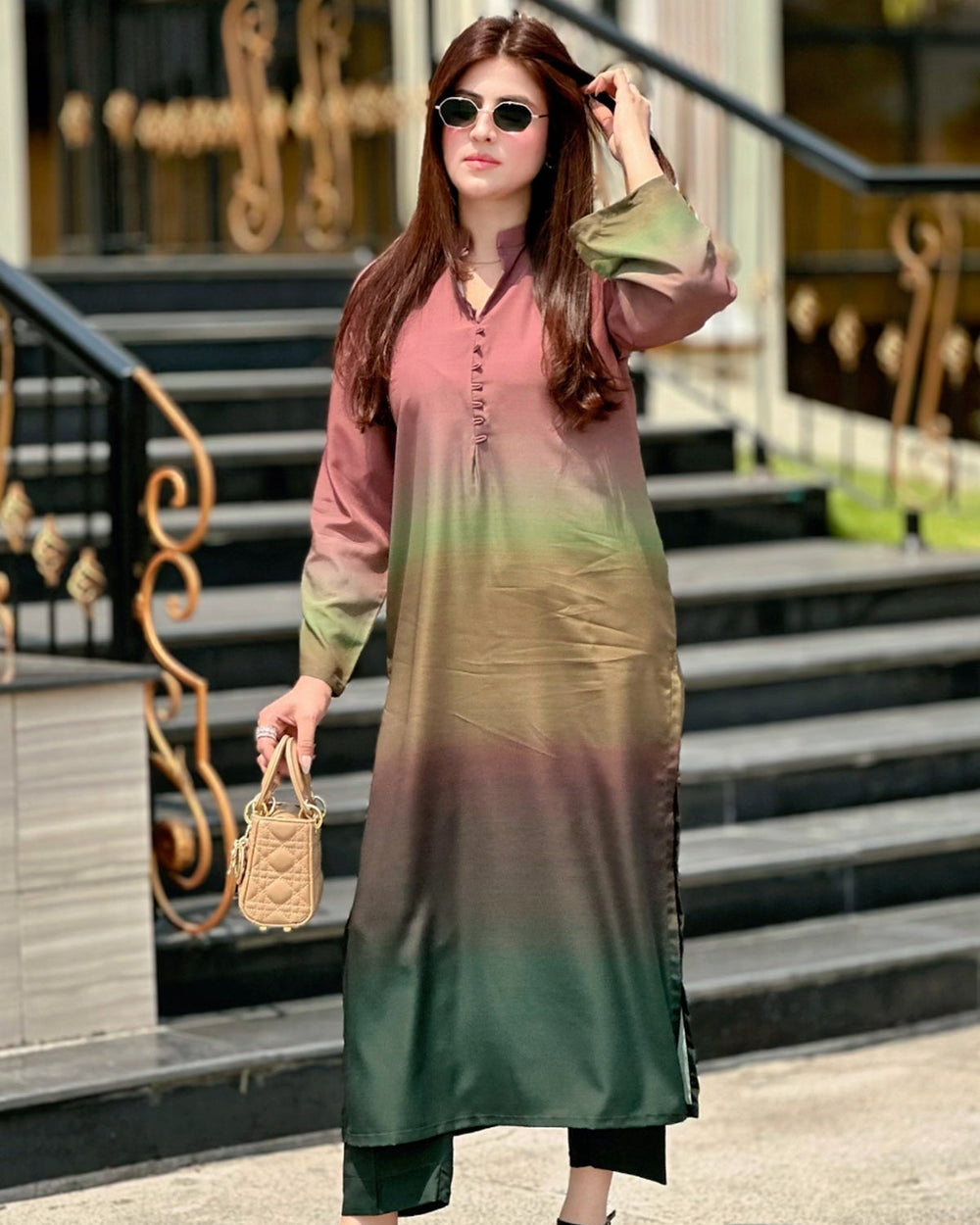 Woman wearing a gradient dress with pink and green colors, standing outdoors.