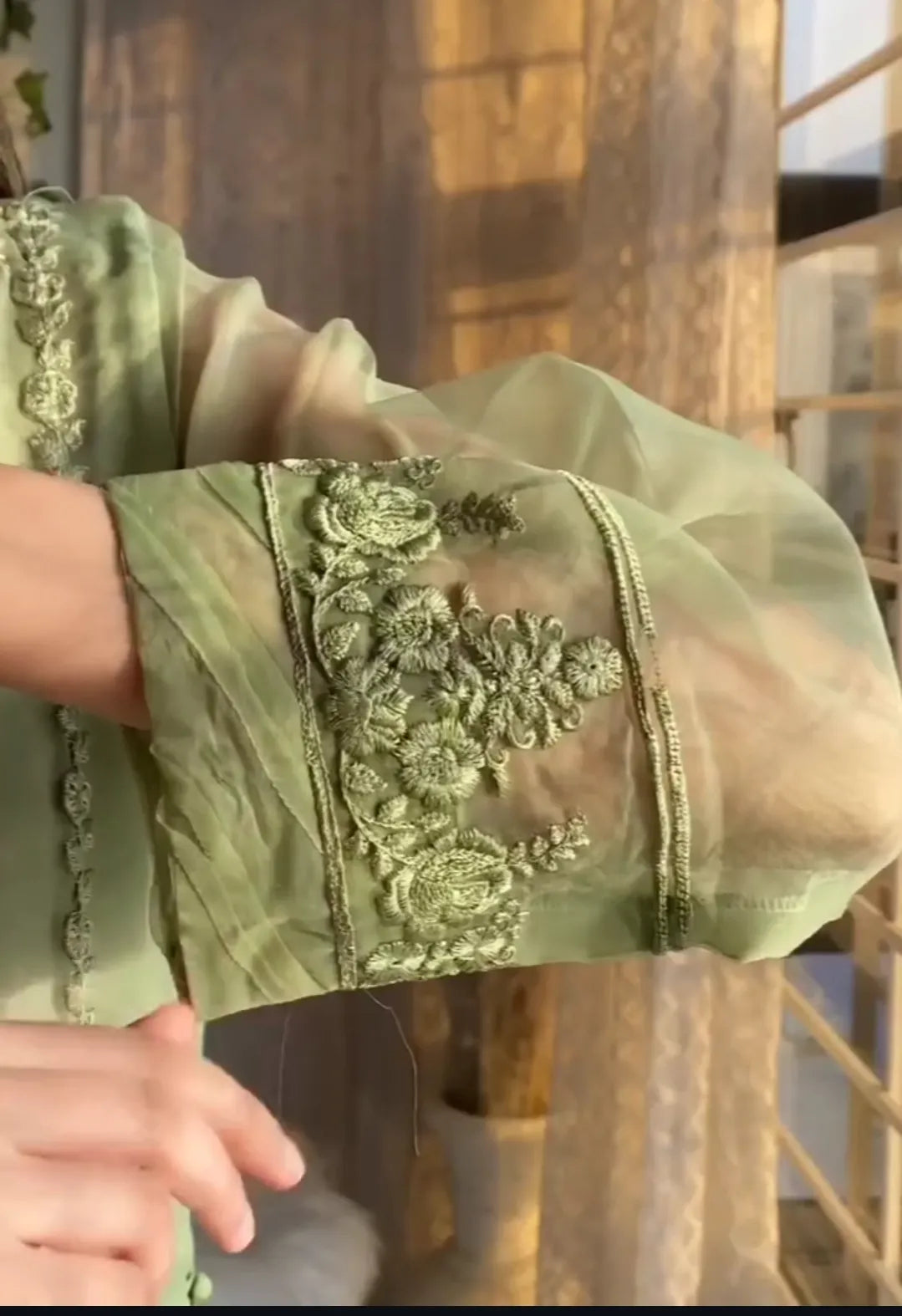 Close-up of a green embroidered fabric with floral patterns.