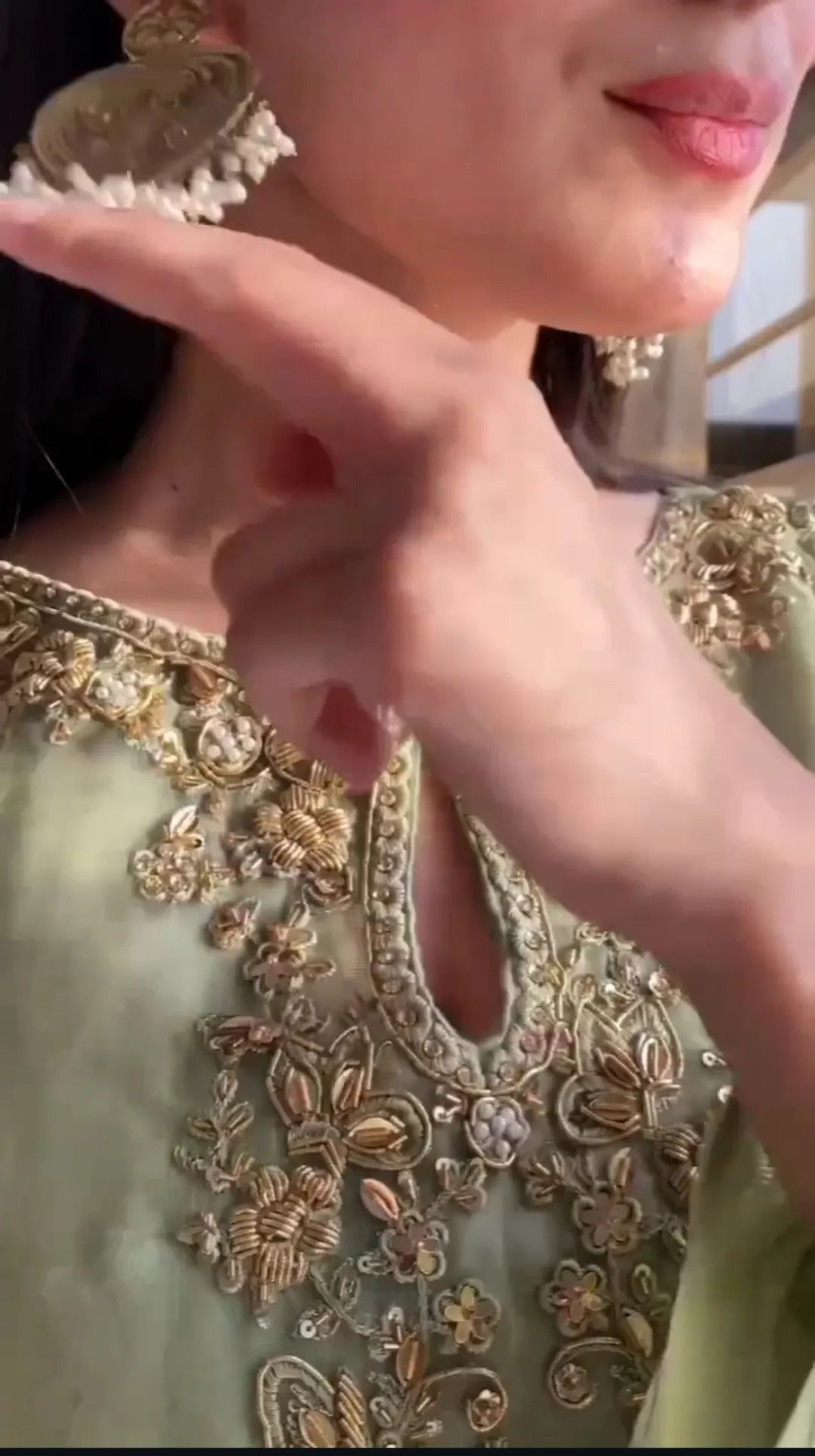 Close-up of a person wearing a green embroidered outfit with gold detailing.