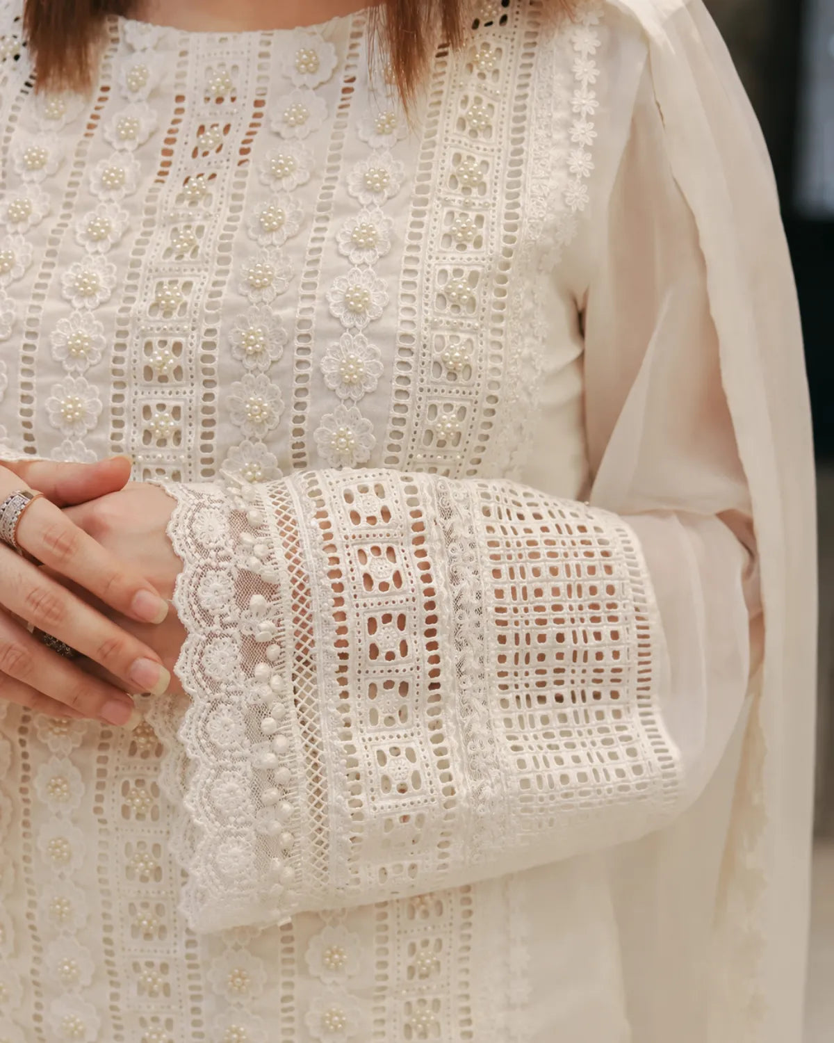 Close-up of a person wearing a white embroidered outfit with a sheer dupatta.